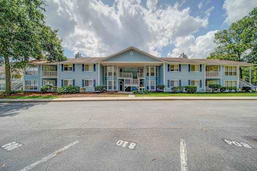 Apartment complex with a parking lot in front.