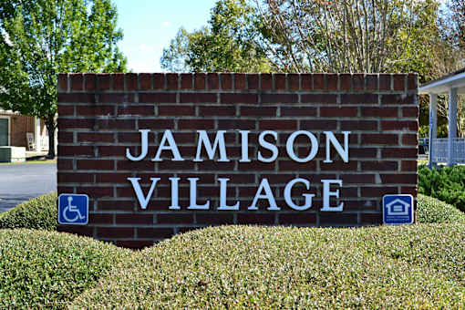 A sign that says Jamison Village in front of a building.
