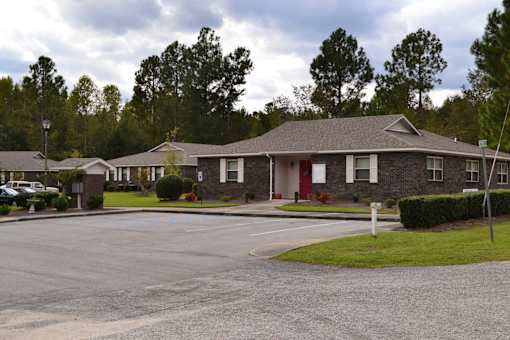 A building with a red door is surrounded by a parking lot.