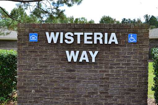 A sign that says Wisteria Way in front of a building.