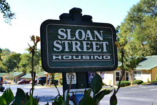 A sign for Sloan Street Housing stands in front of a building.