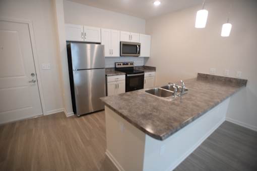 A kitchen with a stainless steel refrigerator and a microwave above the stove.