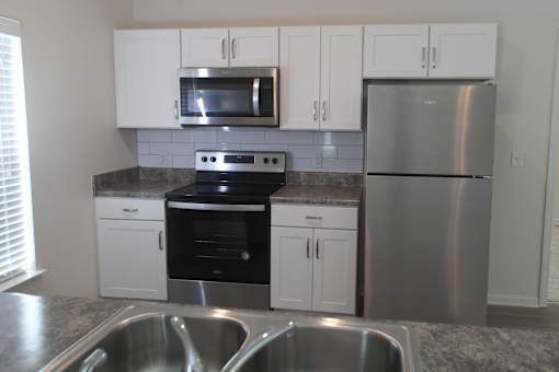 A kitchen with a stainless steel refrigerator, microwave, oven, and sink.