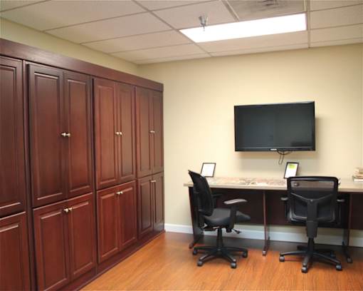A room with a desk, chairs and cabinets.