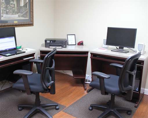 The business center at Croft House Elderly Apartments, featuring two computers, a printer and swivel chairs.