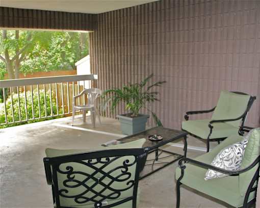 A porch at Croft House Elderly Apartments with green chairs, a plant and a table
