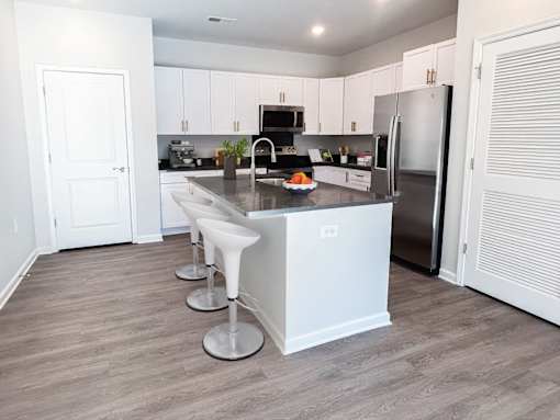 A kitchen with white cabinets and a stainless steel refrigerator.