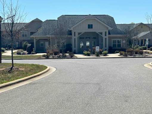 A large building with a grey roof and a driveway in front.