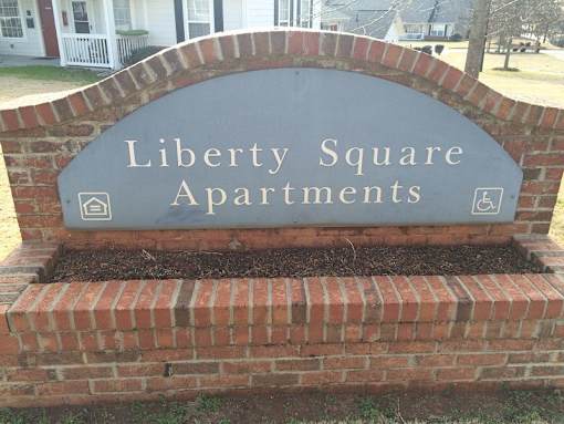 A sign for Liberty Square Apartments is displayed on a brick wall.