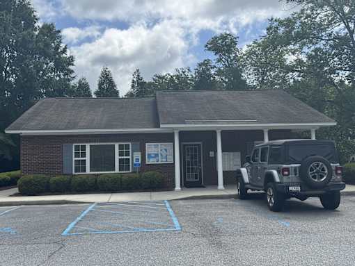 A black jeep is parked in front of a building with a parking lot.