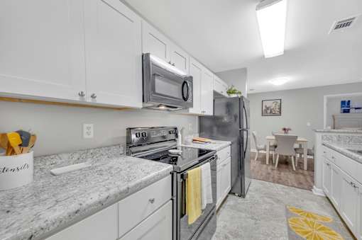 A kitchen with white cabinets and a granite countertop.