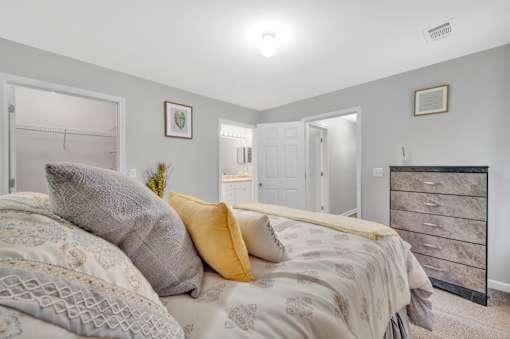 A bedroom with a bed, dresser, and two framed pictures on the wall.