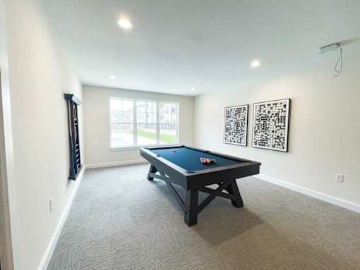 A pool table in a room with two framed QR codes on the wall.