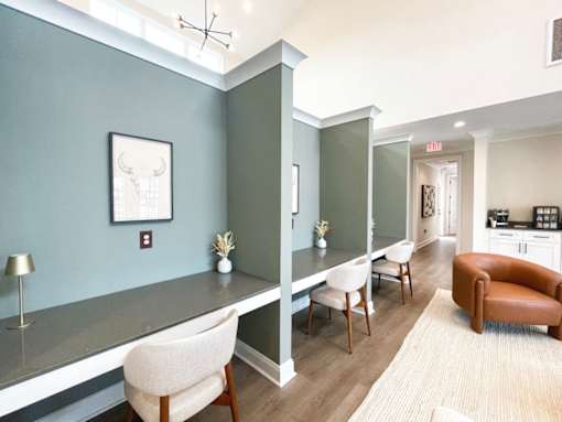 A room with a grey counter and white chairs.