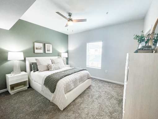 A bedroom with a bed, nightstand, and a ceiling fan.