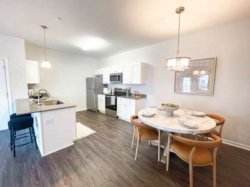 A modern kitchen with a dining table set for two.