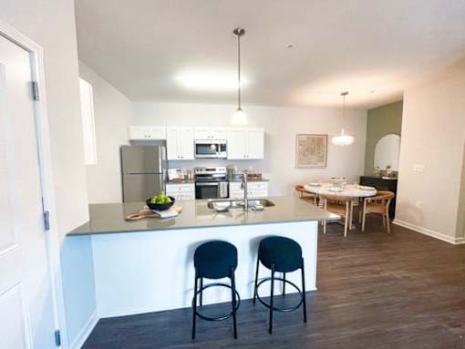 A kitchen with a bar and two chairs.