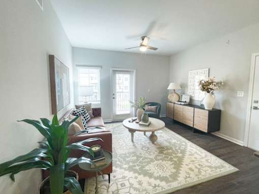 A living room with a couch, a chair, a coffee table, and a potted plant.