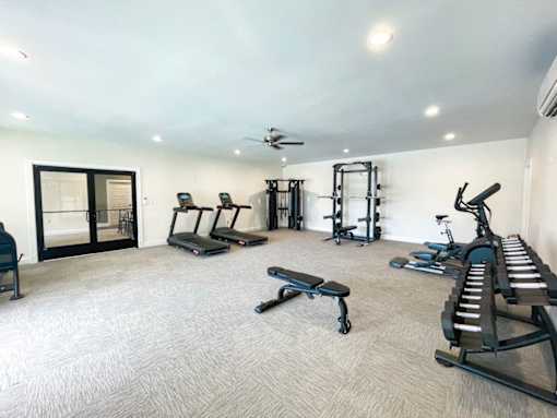 A spacious gym with a variety of equipment including treadmills, weights, and a bench press.