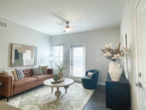 A living room with a brown couch, a round table, and a blue chair.