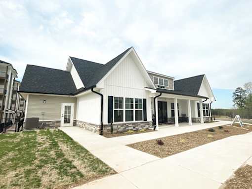 A white house with a black roof and a grey garage door.