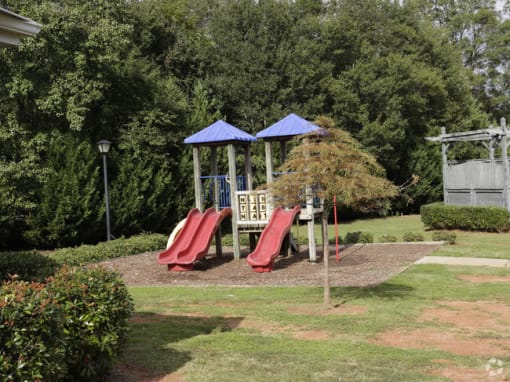 a playground with two slides and two umbrellas in a park