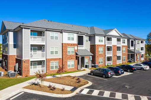 A large apartment complex with a parking lot in front.