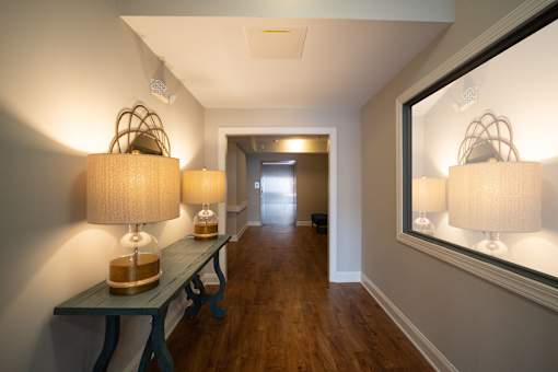 A hallway with a bench and two lamps on the wall.