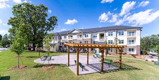 A large building with a white and grey exterior and a wooden pergola in front.
