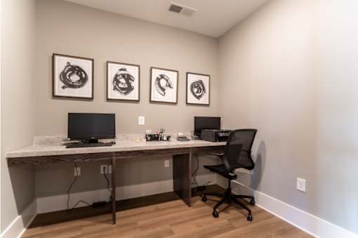 A room with a desk, chair, and three framed pictures on the wall.