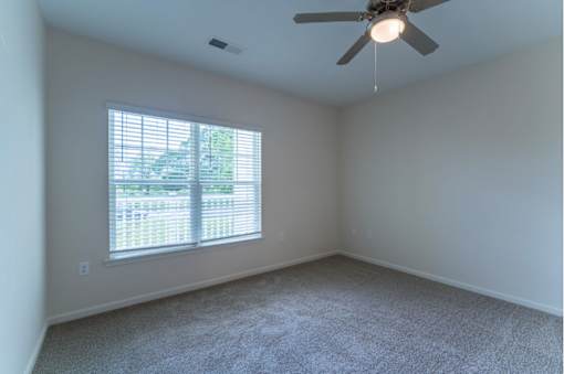 A room with a ceiling fan and a window with blinds.