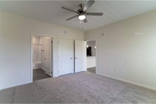 A room with a ceiling fan and carpeted floor.