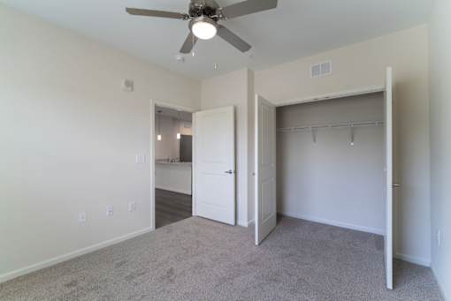 A room with a ceiling fan and a closet.