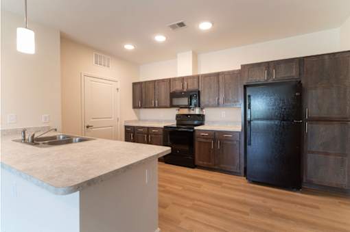 A kitchen with a black refrigerator and wooden cabinets.