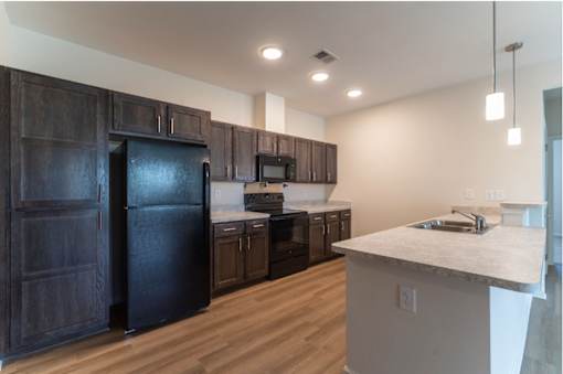 A kitchen with dark wood cabinets and a black refrigerator.