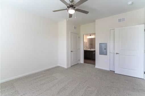 A room with a ceiling fan and carpeted floor.