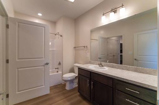 A bathroom with a toilet, sink, and mirror.