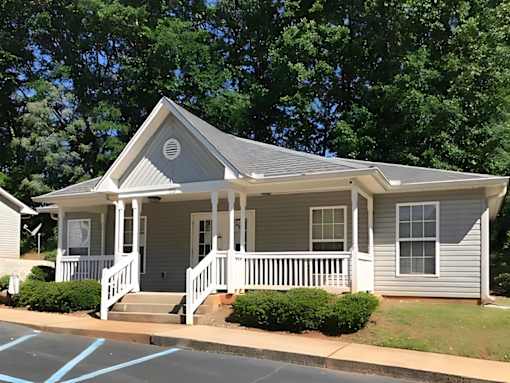 A small house with a porch and a front yard.