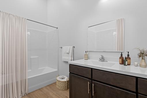 A bathroom with a white sink, a mirror, and a shower with a curtain.