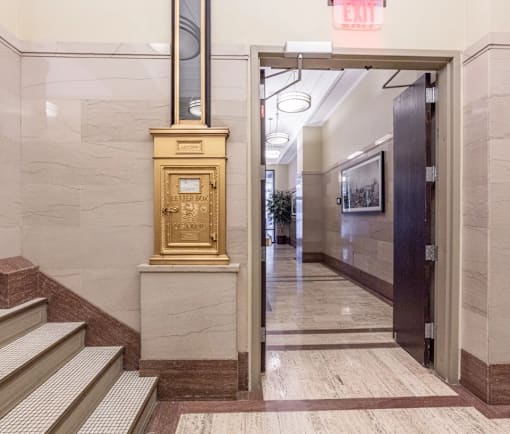 A gold safe is on a marble floor next to a staircase.