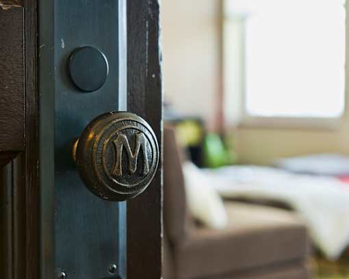 A black door with a round knob and a letter M engraved on it.