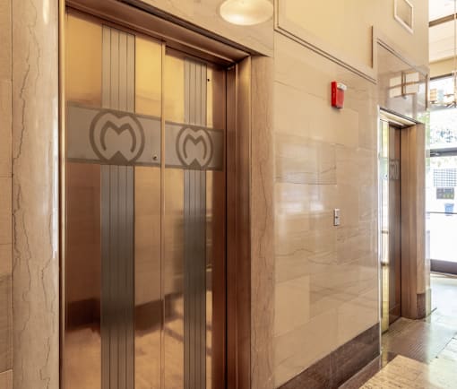 A set of elevator doors with a heart-shaped logo on the glass.