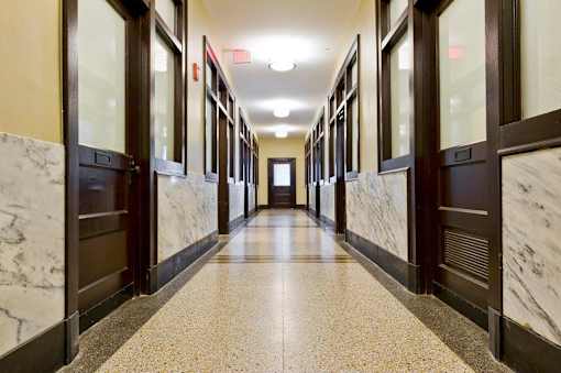 A long hallway with marble floors and doors on both sides.