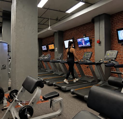 A woman is running on a treadmill in a gym.