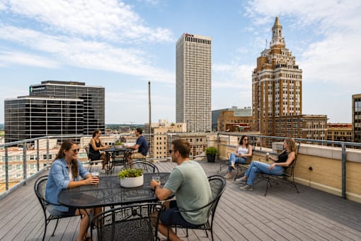 A group of people are sitting around a table on a rooftop patio.