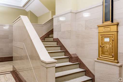 A staircase with a gold mailbox on the wall.