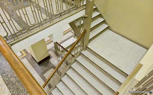 A staircase with a metal railing and wooden handrail.