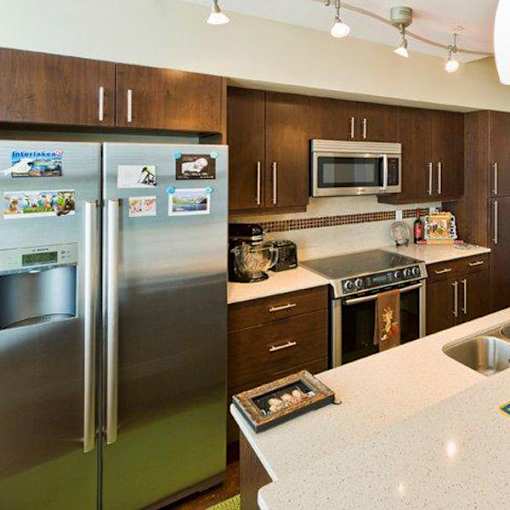 A modern kitchen with a stainless steel refrigerator and a microwave above the stove.