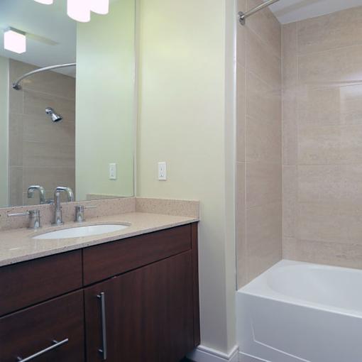 A bathroom with a sink, mirror, and tub.