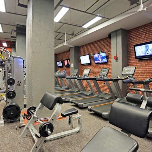 A gym with treadmills, weight machines, and televisions on the wall.